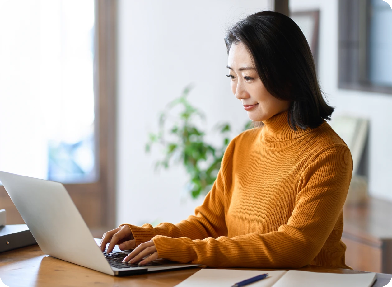 Woman in orange sweater using laptop